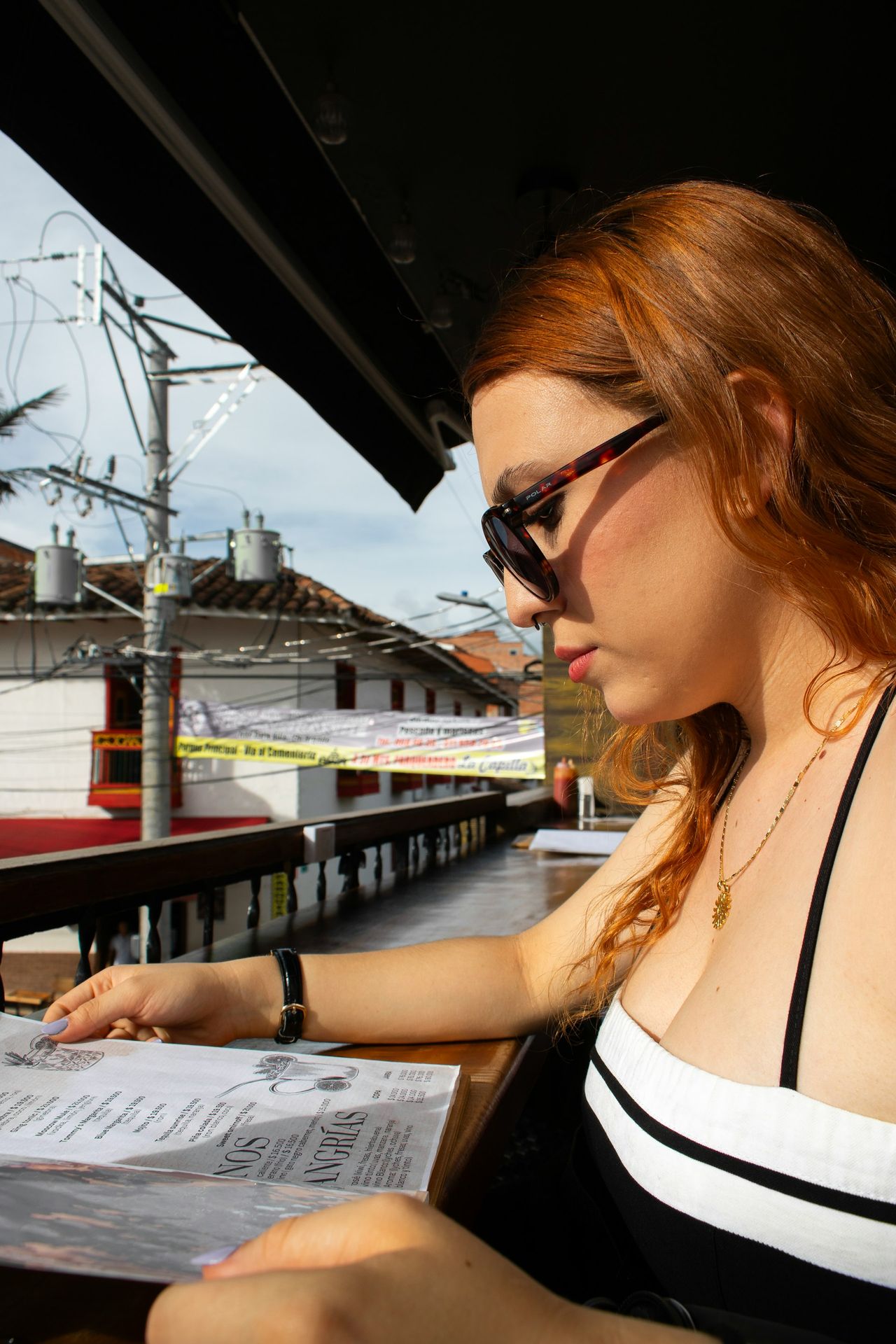 Woman reads a menu at an outdoor restaurant.